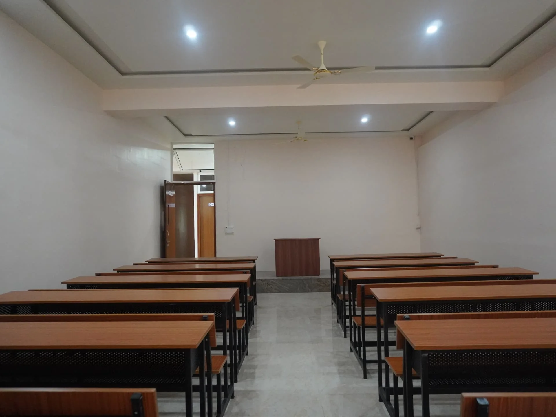 Class room arranged with rows of desks and a lectern for regular teaching