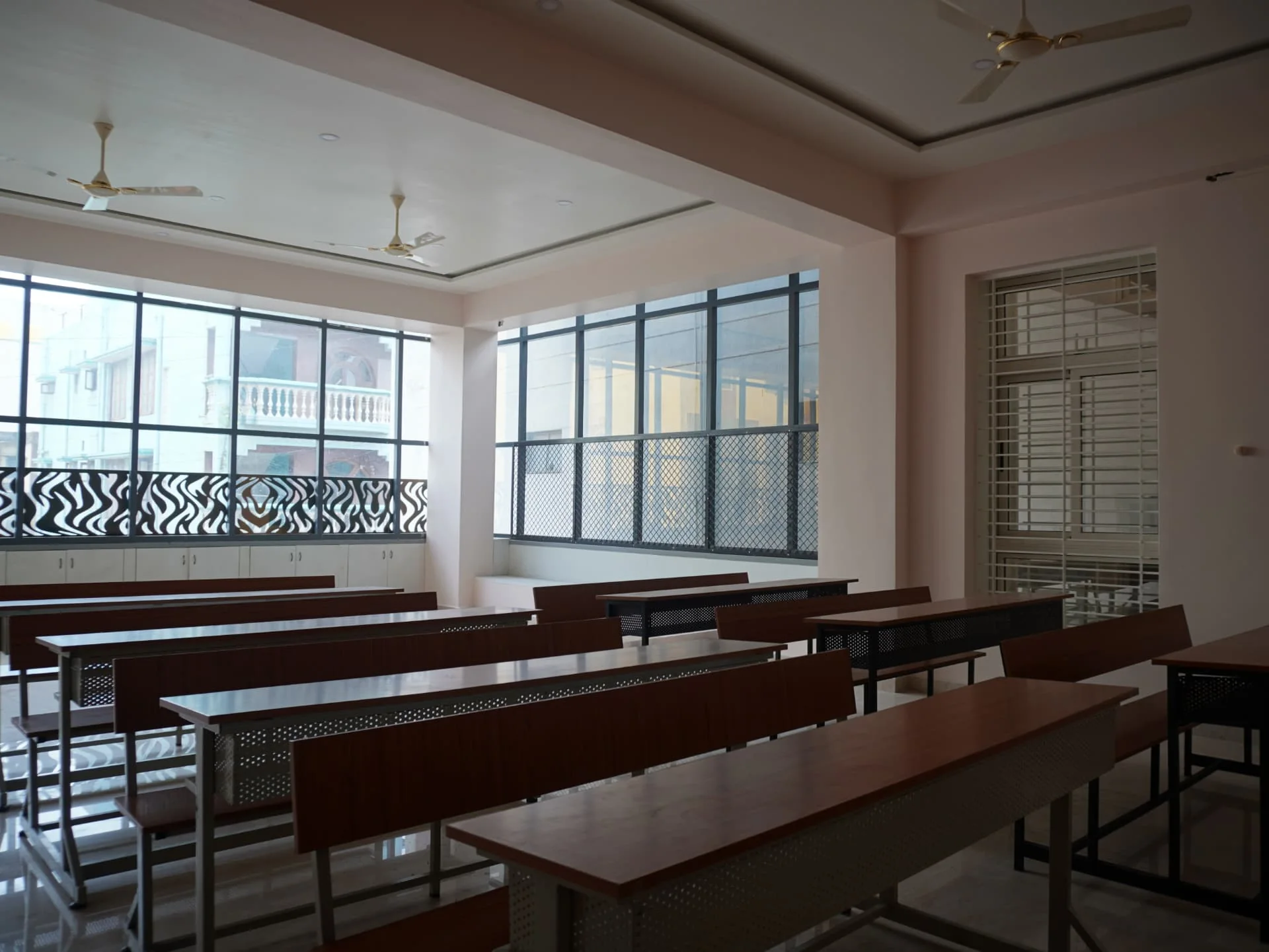 Bright class room with rows of student desks and full-height windows at the College