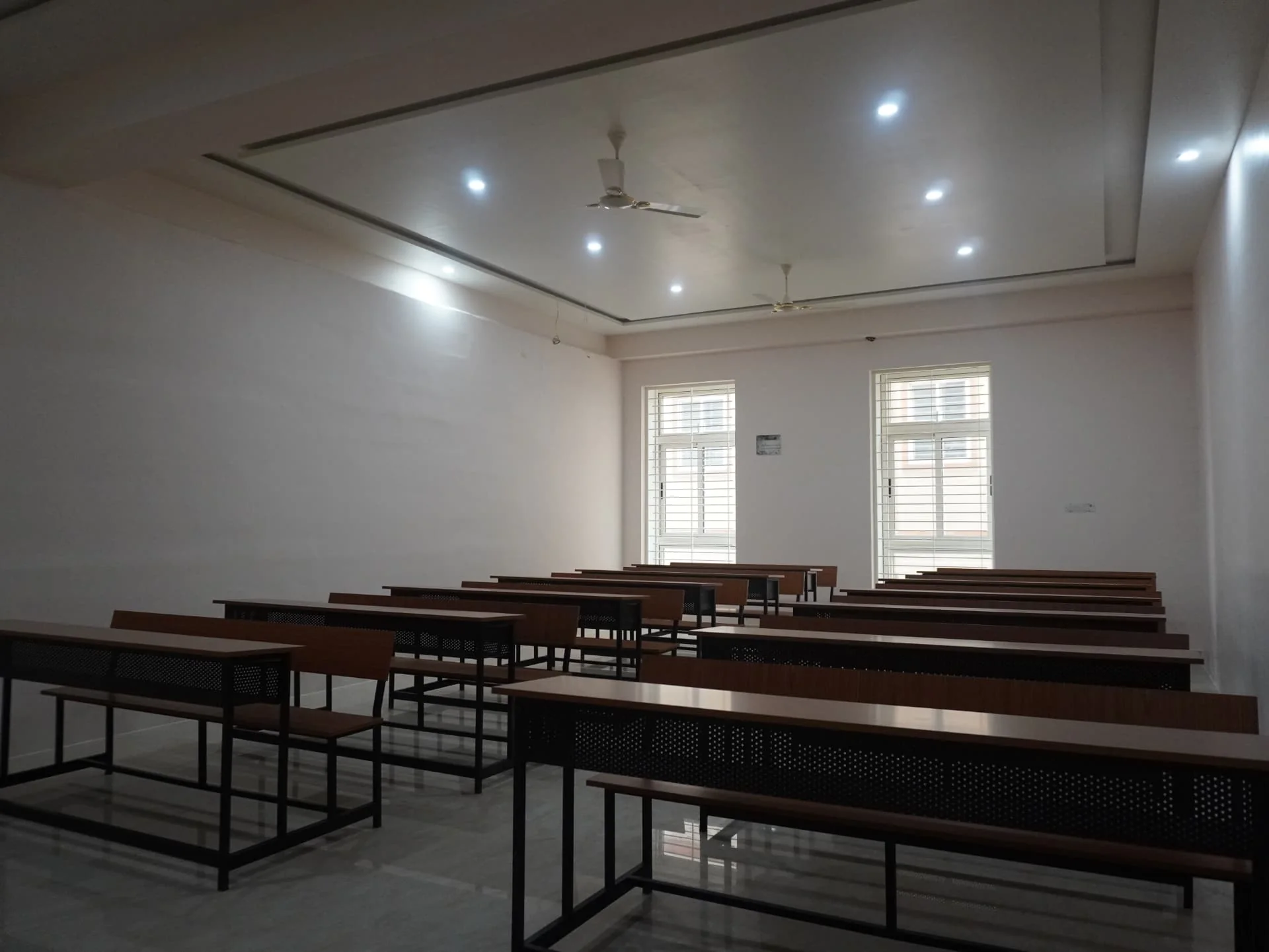 Lecture room with student benches, ceiling fans and natural light from classroom windows