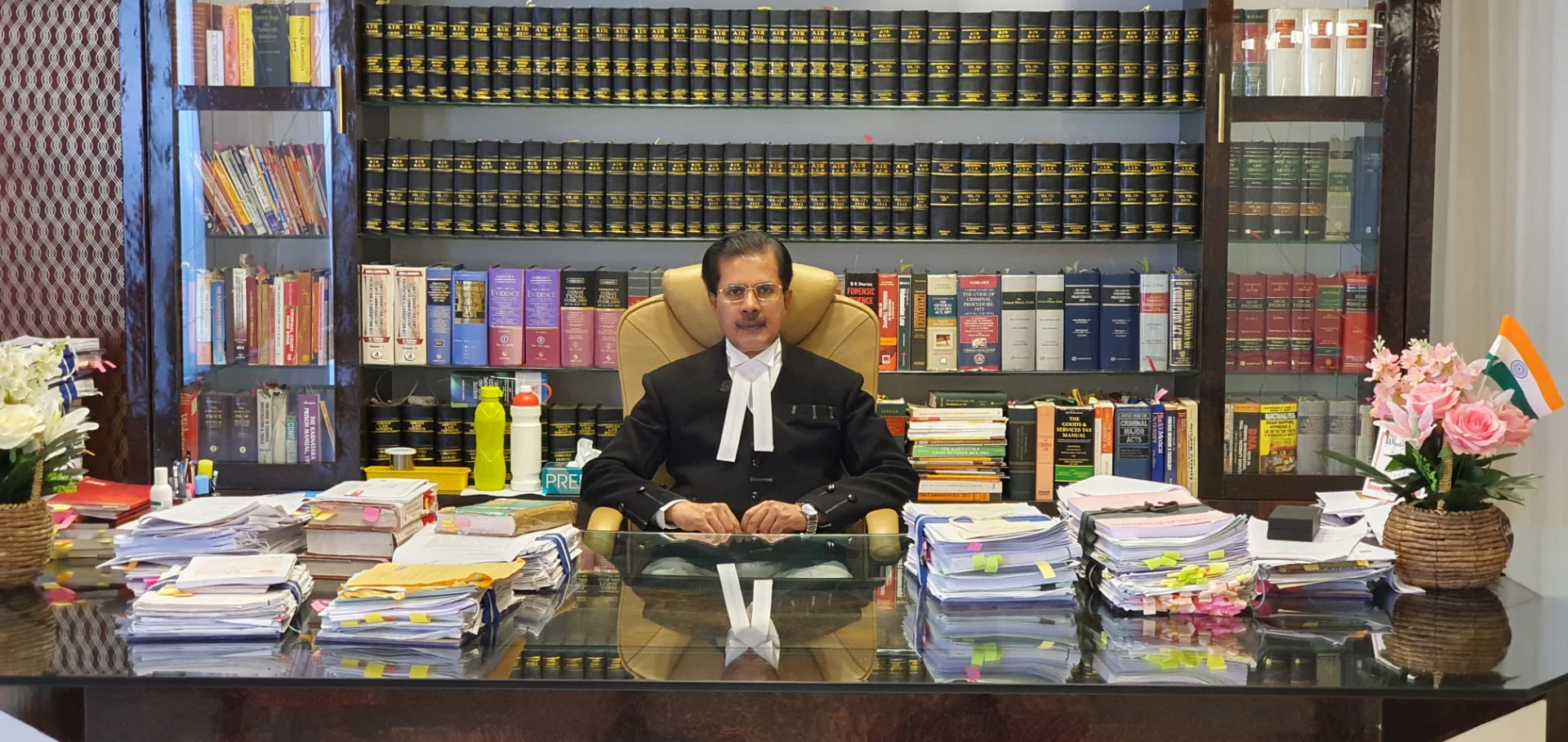 Senior Advocate Hashmath Pasha, Founder of the College, seated at his desk in chambers with shelves of law books behind him